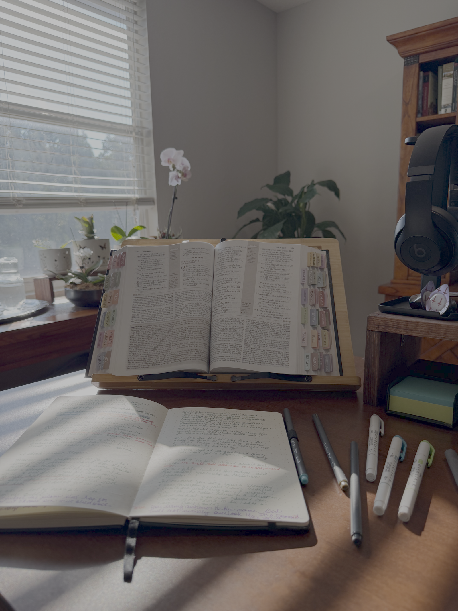 Bible on stand with journal and pens on the desk